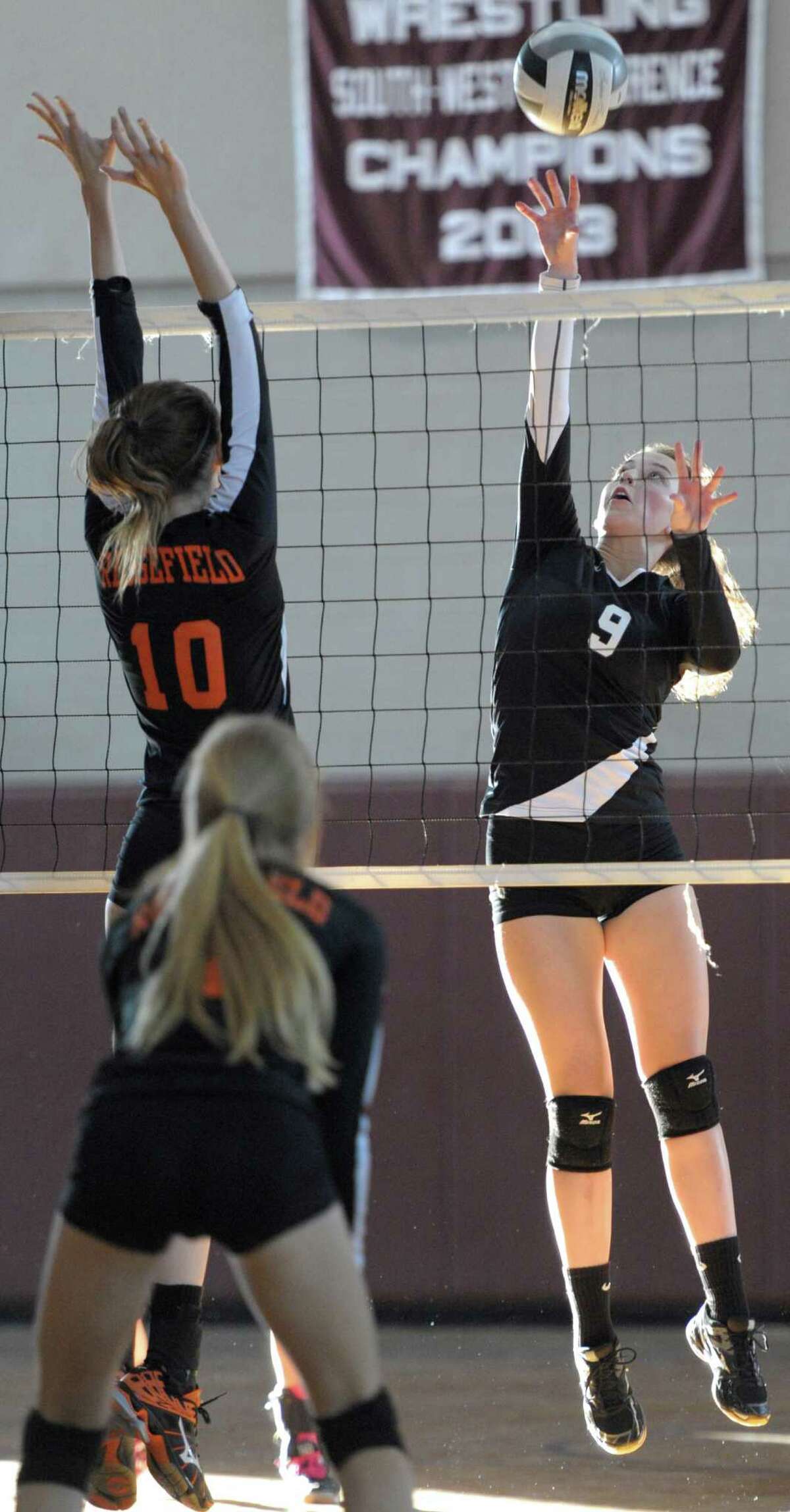 Bethel's Jessy Demment (9) goes to tap the ball over the net as Ridgefield's Sydney Carroll (10) goes for the block in the girls high school volleyball game between Ridgefield and Bethel high schools on Wednesday afternoon, September 16, 2015, in Bethel, Conn.