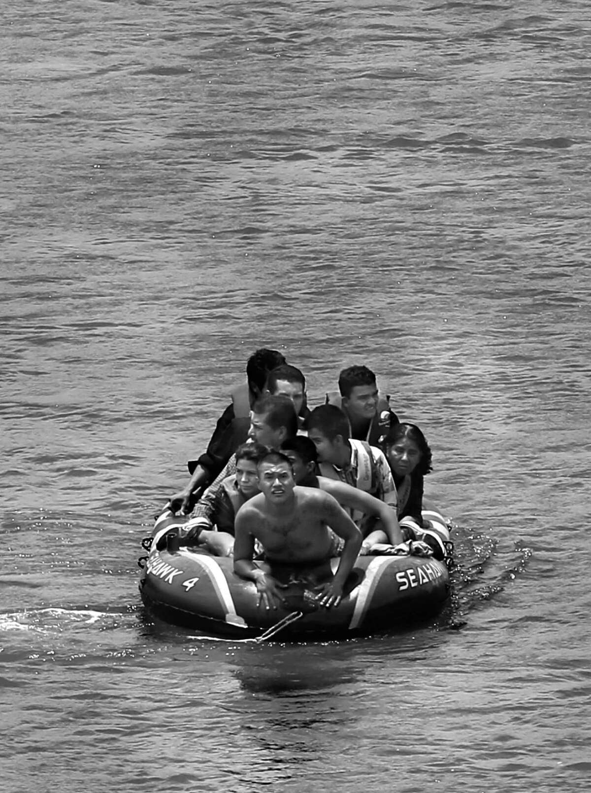 JUNE 24, 2014, 2:02 PM, ROMA, TEXAS - Using an inflatable raft, coyotes, or smugglers, carry immigrants across by the international bridge on the Rio Grande in Roma, Texas. According to law enforcement officials, higher risk smuggling operations have moved into Starr County in order to avoid the saturated border in Hidalgo, County.