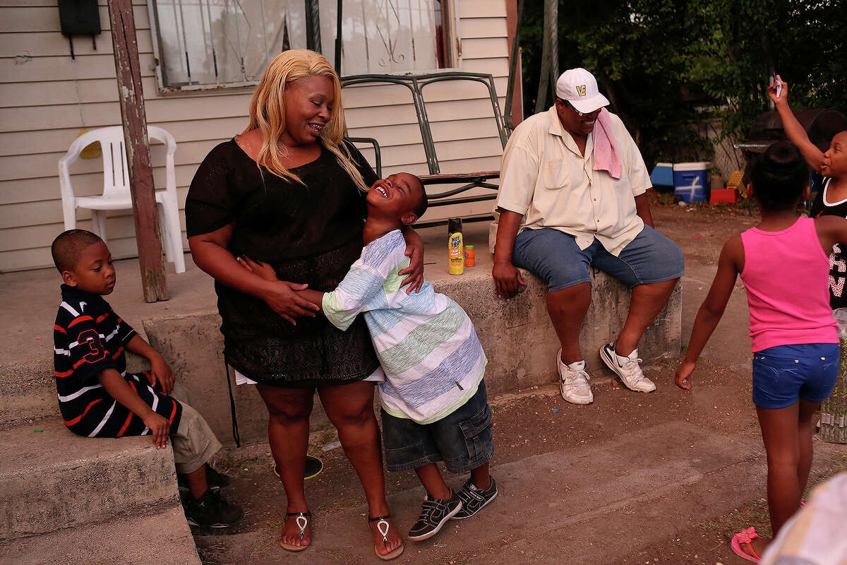 Tamika Winn is embraced by her son, Trezvant Mason, 7, as they spend the evening with their family, as they do most evenings, at the East Side home owned by Winn's grandmother, Gloria Nelson, 88, in July 2014.