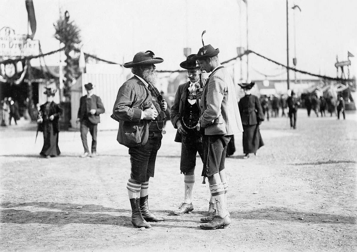 Three Bavarians wearing Lederhosen and traditional jackets and hats around 1910 at Oktoberfest.