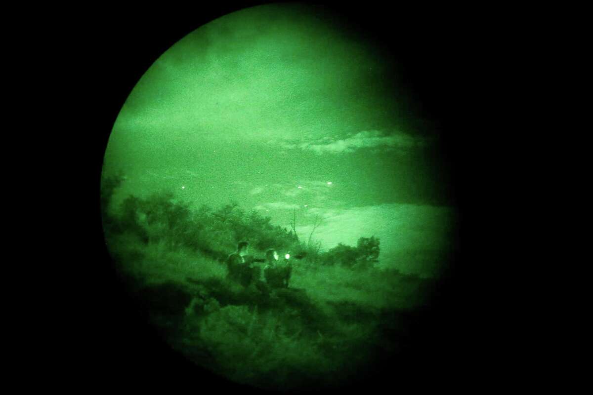 FILE: As seen through night vision goggles, two enlisted officers from the U.S. Army Special Operations Public Affairs Office watch C-17 transports (seen as white dots in the sky) fly overhead around 11 p.m. on Tuesday, Aug. 26, 2015, as part of a special warfare training exercise held at Camp Bullis. The exercises were a continuation of military exercises as some referred to as "Jade Helm 15."