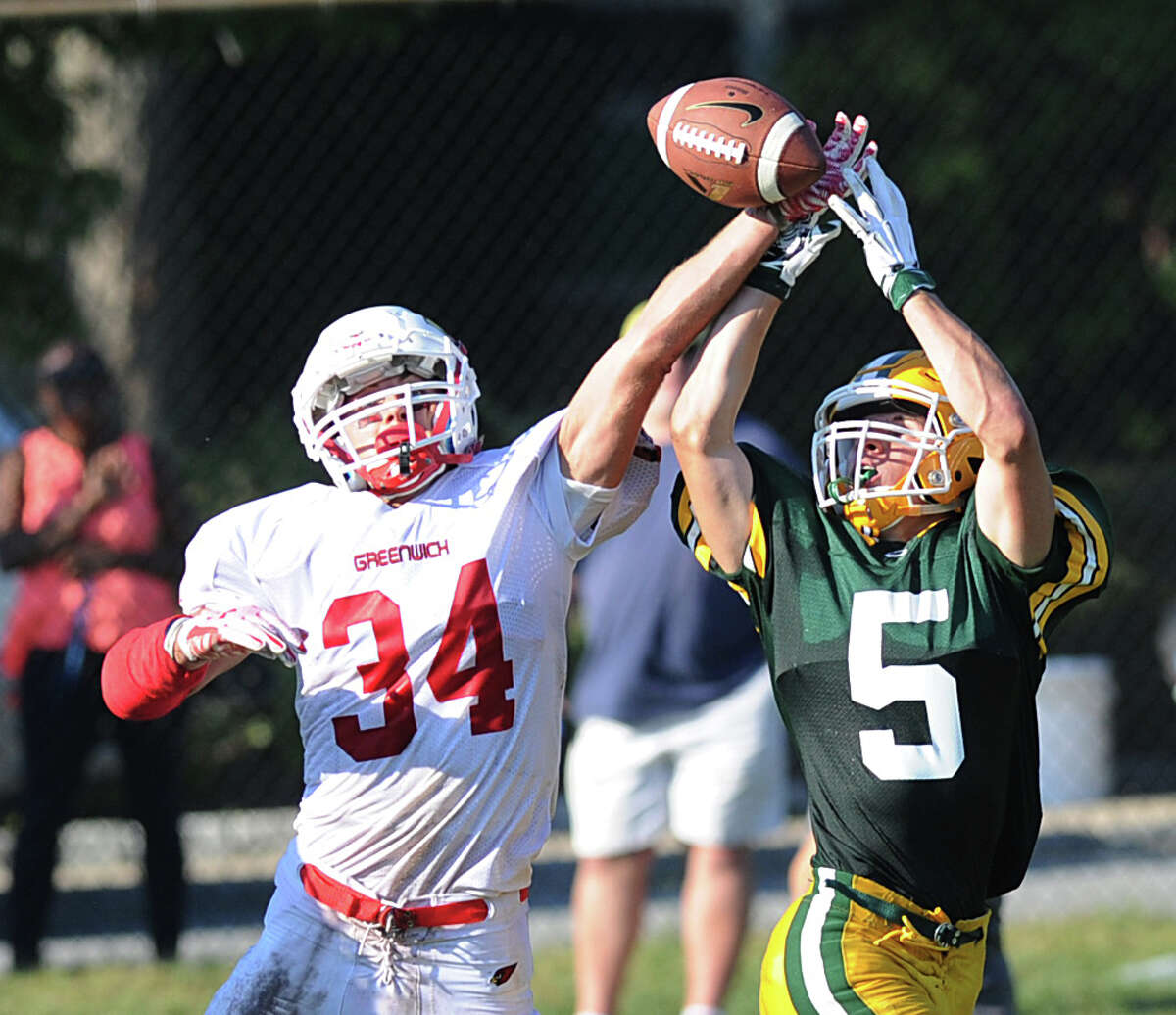 Greenwich defender Mike Gianesello (#34), left, breaks up a pass thrown to Trinity's Dominick Svrcek (#5), right, during the high school football game between Trinity Catholic High School and Greenwich High School at Trinity in Stamford, Conn., Friday, Sept. 18, 2015. Greenwich won the game, 42-38.
