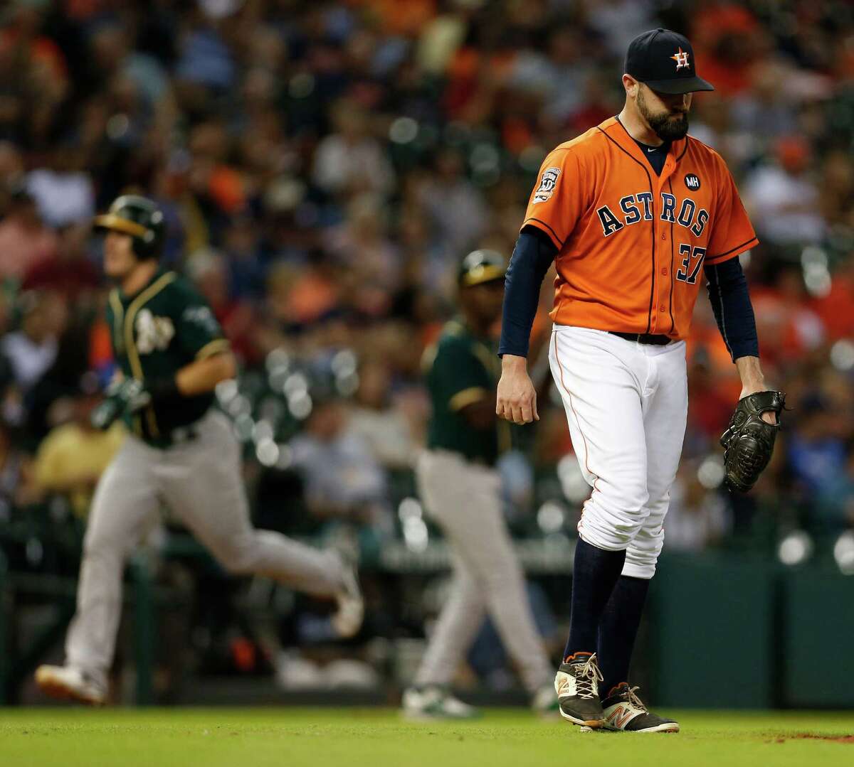 Astros relief pitcher Pat Neshek, right, can't bear to watch as the Athletics' Danny Valencia rounds the bases after hitting a decisive two-run homer in the eighth inning Friday night at Minute Maid Park.