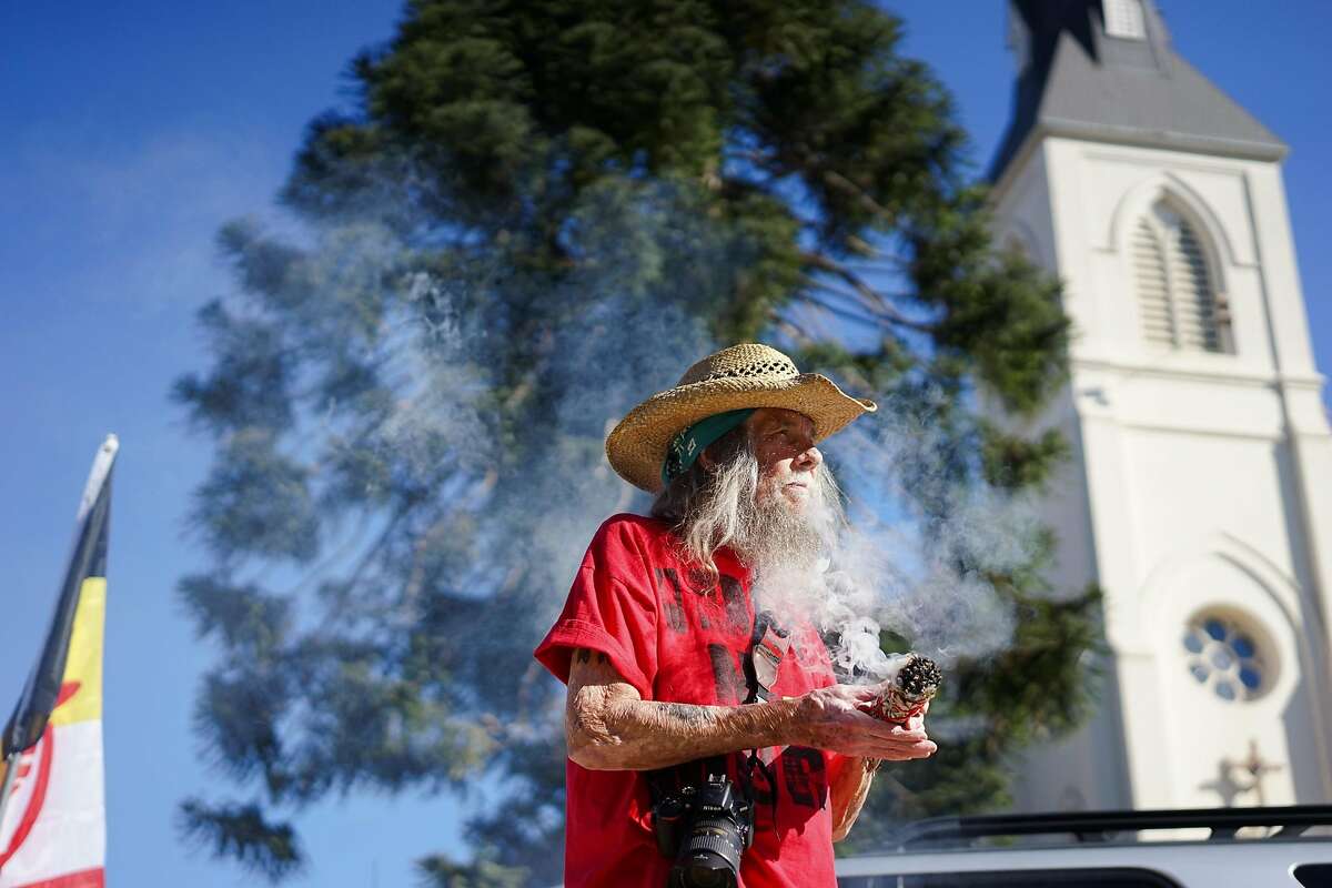 Autumn Sun cleanses himself with sage at Holy Cross Church in Santa Cruz, Calif. on Saturday Sept. 19, 2015. Tataviam descendants Caroline Ward Holland and Kagen Holland are leading the Walk for the Ancestors which will visit every mission in protest of the canonization of Junipero Serra.