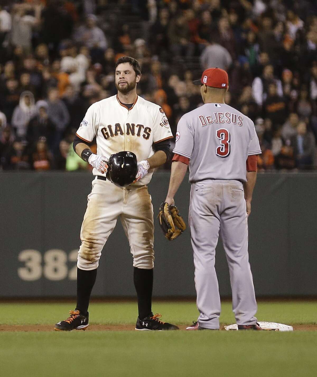 Reds infielder Ivan De Jesus checks on Brandon Belt after accidentally kneeing the Giants in the helmet Sept. 15, causing his latest concussion.