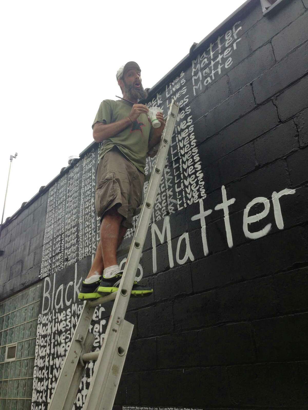 Renda Writer, a white muralist from Miami is expressing his support for the "Black Lives Matter" movement one word at a time on a Detroit art gallery exterior wall, Friday, Sept. 18, 2015, in Detroit. Writer tells The Associated Press that when the commissioned project is completed the phrase will have been written thousands of times. Writer started Monday behind the N'Namdi Center for Contemporary Art and says he is using art "to raise awareness to the disproportionate numbers of blacks being killed by police." (AP Photo/Corey Williams)