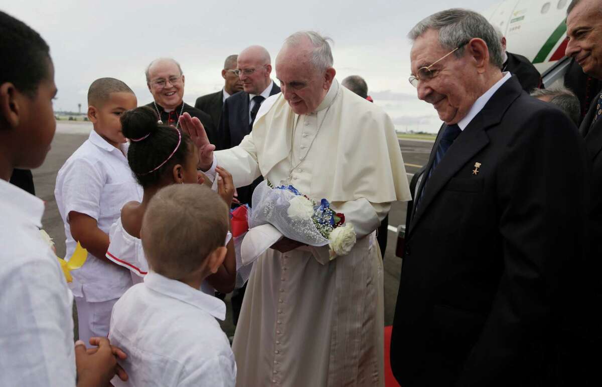 Pope Francis blesses a girl as Cuba's President Raul Castro looks on after landing at the airport in Havana, Cuba, Saturday, Sept. 19, 2015. Pope Francis began his 10-day trip to Cuba and the United States, embarking on his first trip to the onetime Cold War foes after helping to nudge forward their historic rapprochement.(Ismael Francisco/Cubadebate Via AP)