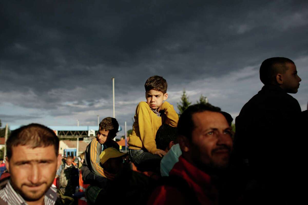 Refugees line up to cross the border from Croatia to the Slovenian village Rigonce at the border station in Harmica, Croatia, Sunday, Sept. 20, 2015. The refugees enter a bus for transport to a registration center. (AP Photo/Markus Schreiber)