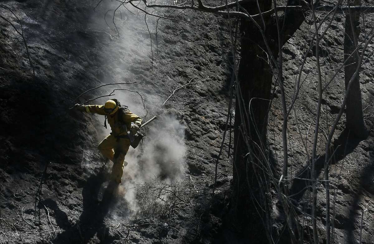 Xavier Lugo of Cal Fire's Mariposa unit scurries down a steep, ashy slope after working with his crew to put out hot spots during the Tassajara Fire Sept. 22, 2015 in Monterey County, Calif. As of Tuesday morning the fire had destroyed 18 structures, killed one person and was at 65% containment.
