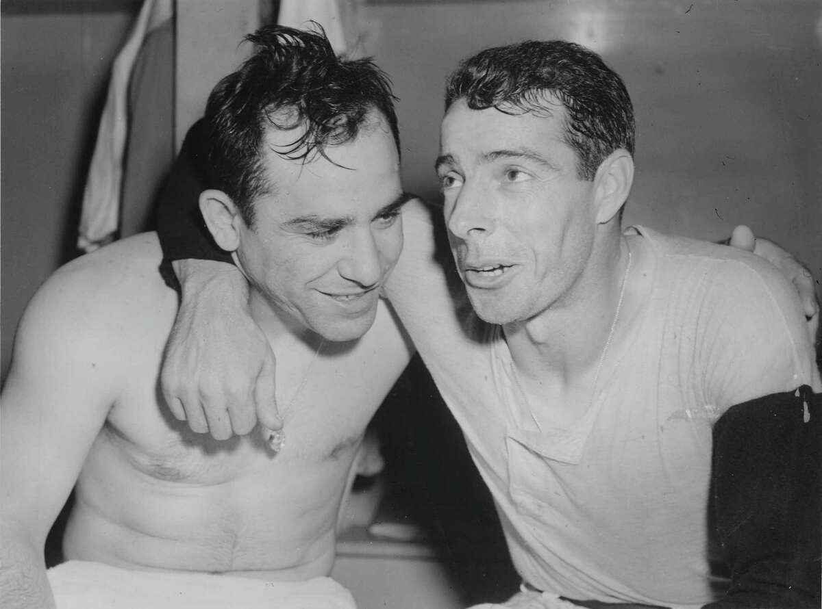 Yogi Berra extends a congratulatory hand as Joe DiMaggio comes