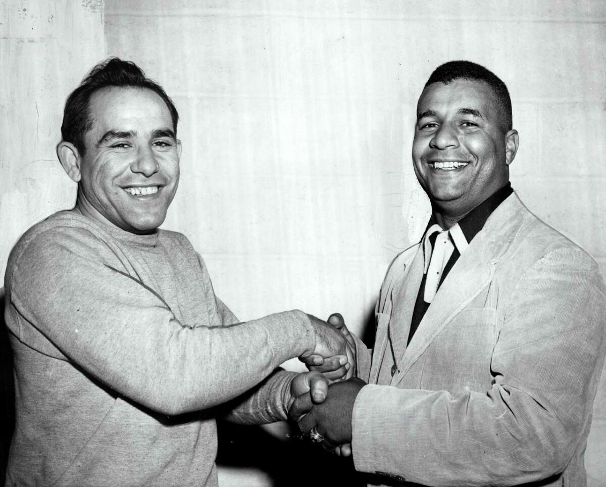 Yogi Berra extends a congratulatory hand as Joe DiMaggio comes