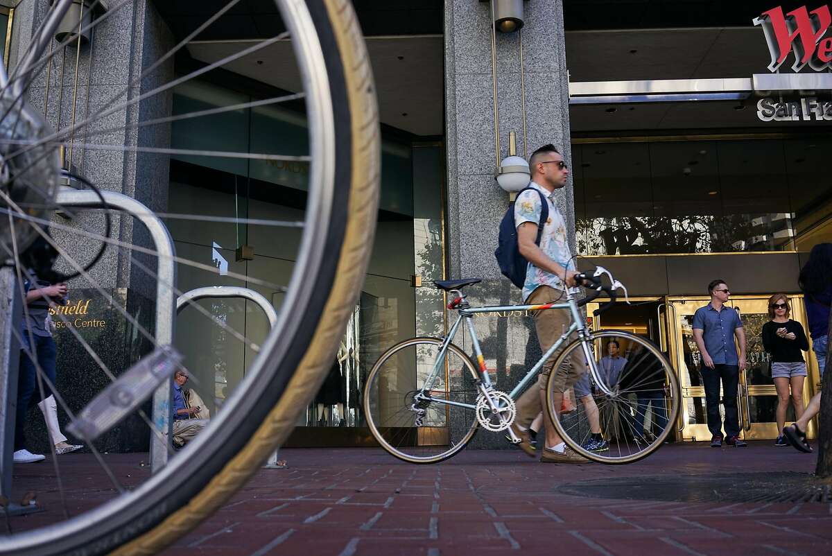 A man passes a locked up bike on Market Street in San Francisco, Calif. on Friday, Sept. 25, 2015. Mayor Ed Lee said he will veto legislation that would require police to make cyclists who don't stop at stop signs a low priority.