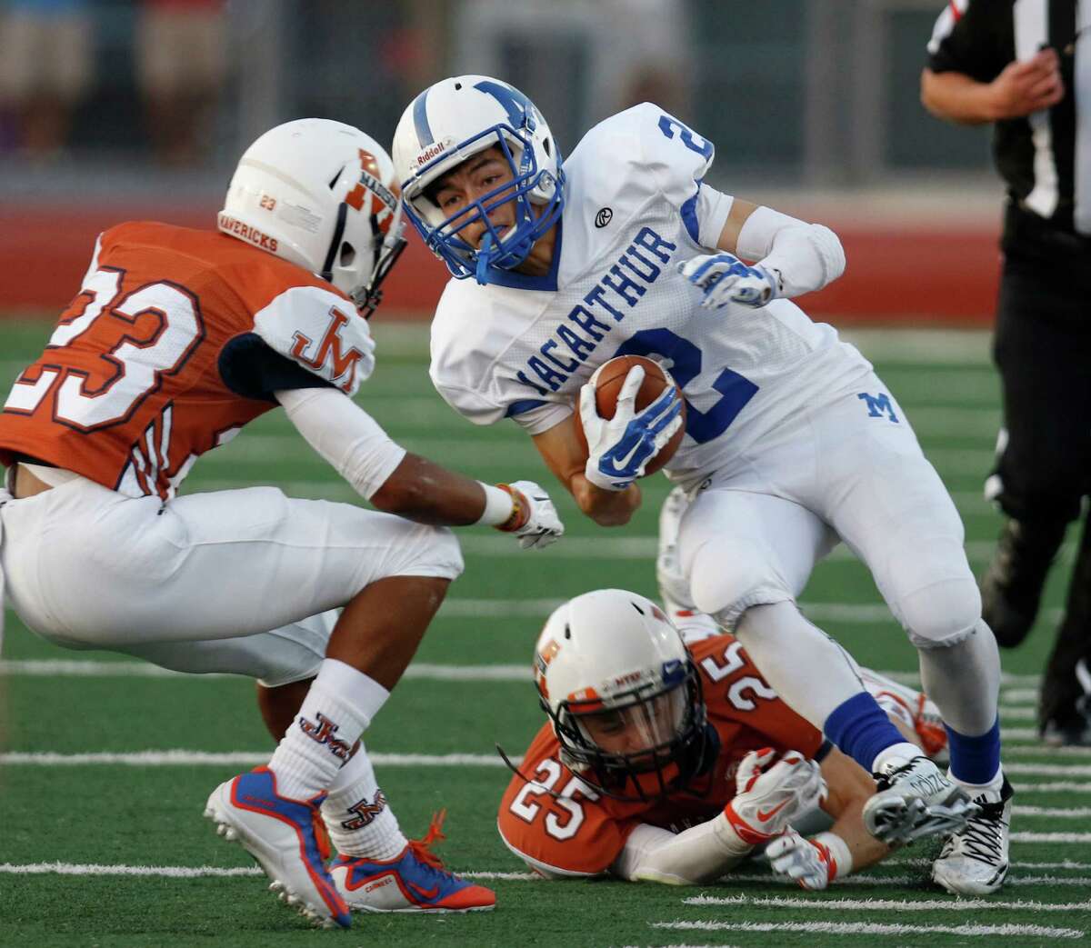 MacArthur's Nate Vega tries to elude the tackle of Madison's Brandon O'Connor and on left is Dante Carheel in first quarter. District 26-6A high school football game between MacArthur and Madison at Comalander Stadium on Saturday, September 26,2015