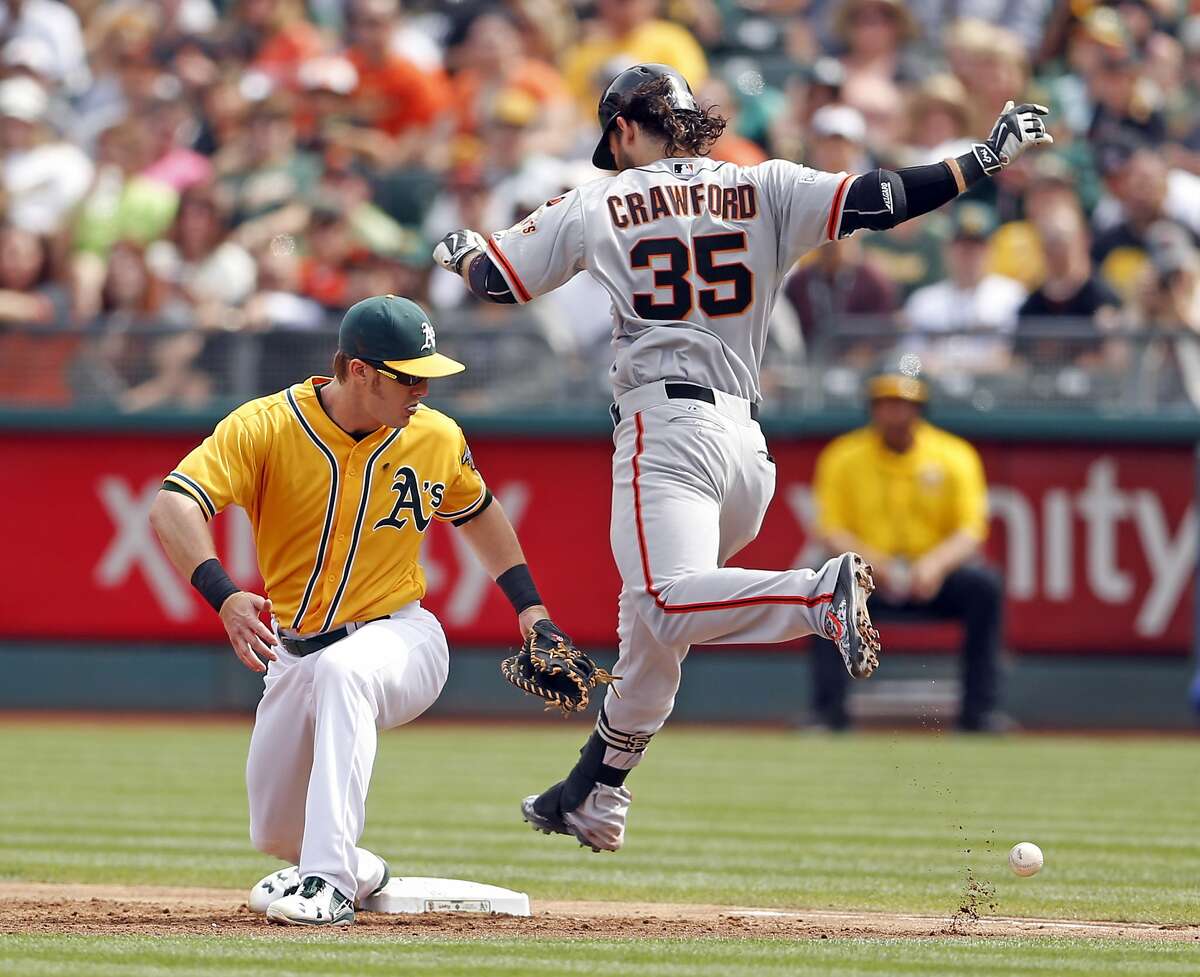 San Francisco Giants' Brandon Crawford reaches base on an error by Oakland A's Brett Lawrie in 3rd inning during MLB game at O.co Coliseum in Oakland, Calif., on Sunday, September 27, 2015.