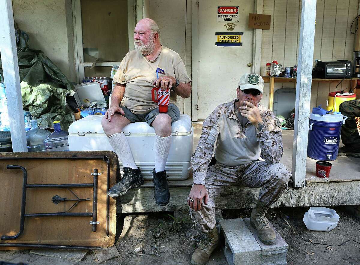 KC Massey, right, takes a drag on a cigarette as he sits with land owner Rusty Monsees Jr. Monsees asked the militia group called Camp Lone Star, to set up camp on his property along the Rio Grande River in Brownsville, TX. Wednesday, September 10, 2014