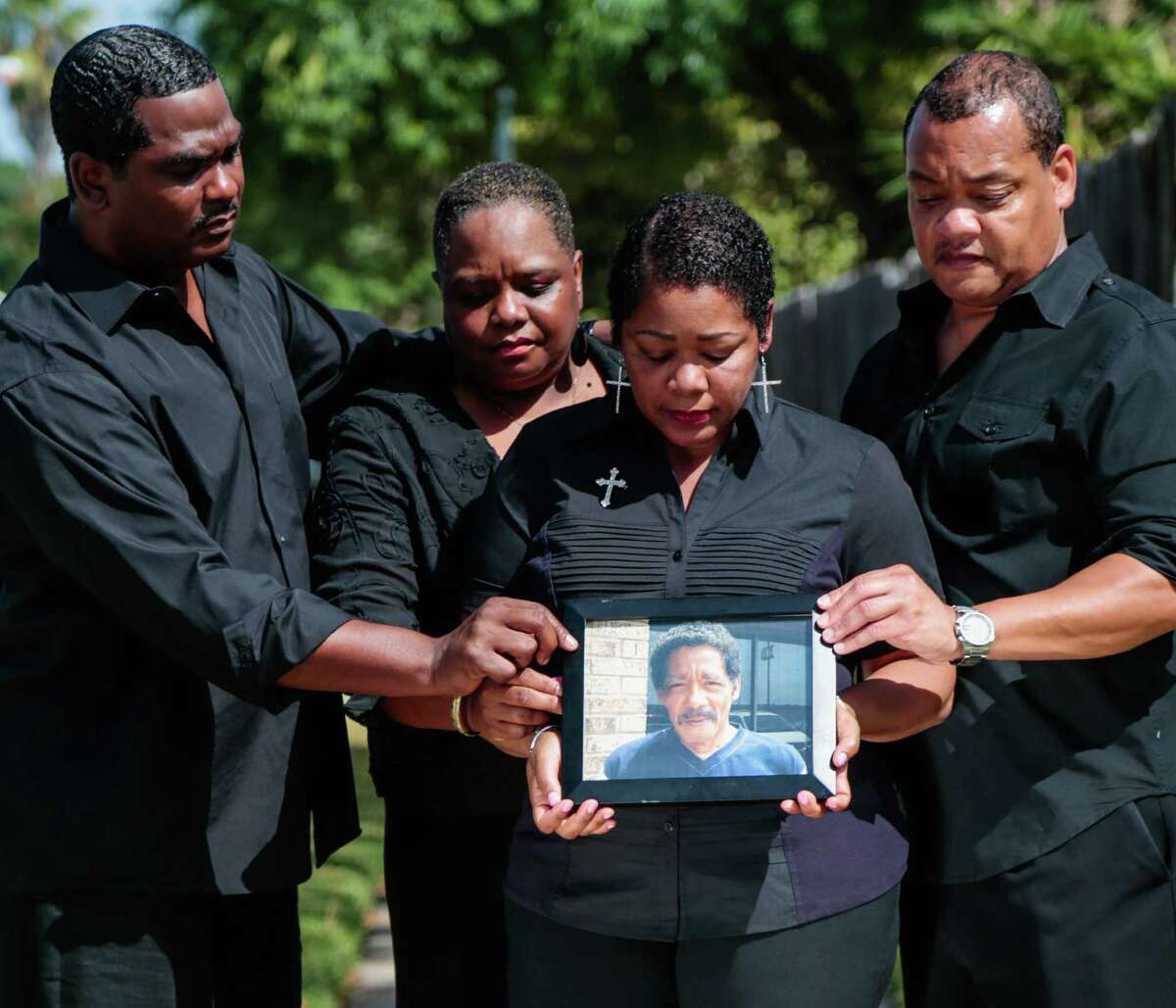 (l-r) Jason Hicks, Marie Hicks-Fields, Evangeline Campbell, and Norman Hicks Jr. all hold on to a photo Norman Hicks Sr.  They have filed a wrongful death lawsuit against Harris County.