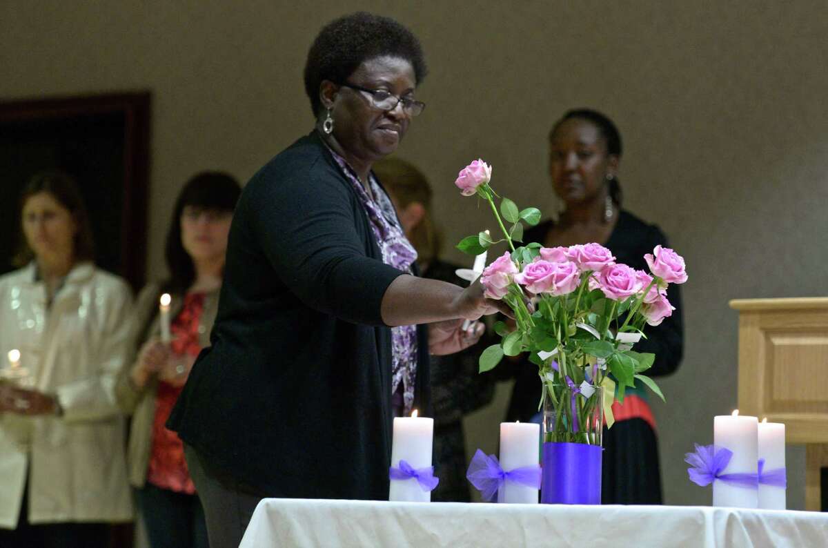 Nana Boateng, of Greenwich, places a flower in a vase during the Greenwich YWCA Domestic Abuse Services Annual Candlelight Vigil on Thursday night, October 1, 2015, in Greenwich, Conn. Each flower represented a person killed by domestic violence in Connecticut last year.