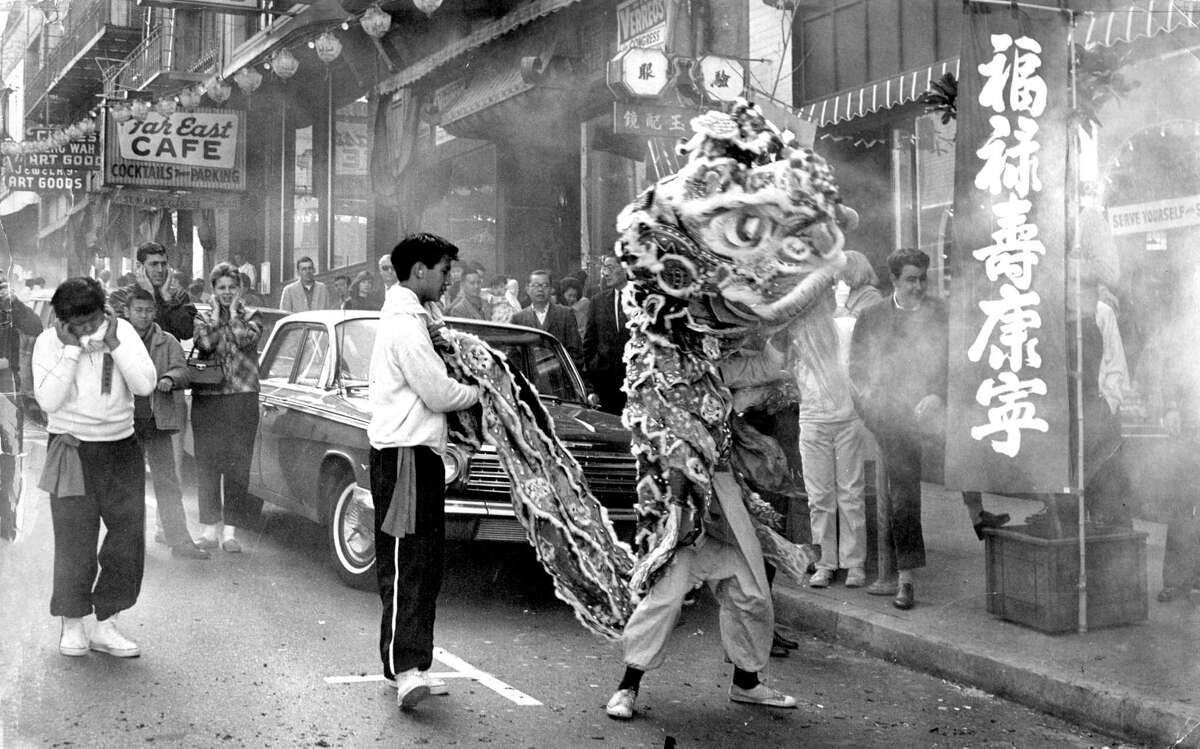 狮子舞蹈演员穿过烟花的阴霾在旧金山的唐人街2月16日1964年。