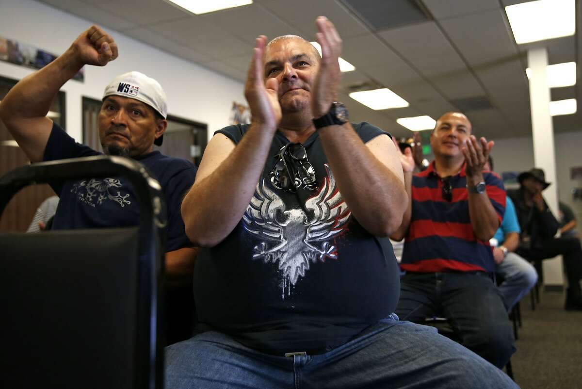 (left to right) Genentech bus drivers' Jose Quindinilla, Mark Zerrilla and Marco Marquez react during a Compass Transportation bus drivers meeting at Teamsters Local 853 in San Leandro, Calif., on Saturday, October 3, 2015.