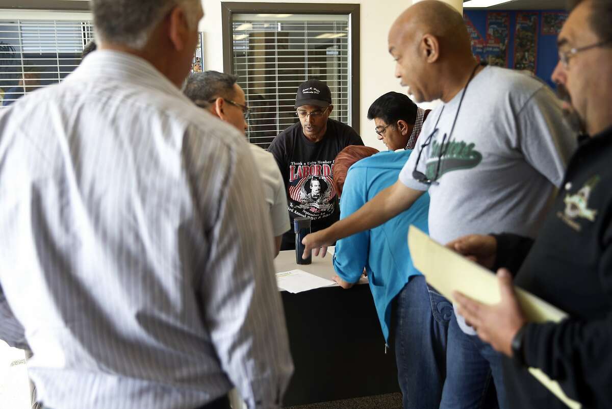 Teamsters Local 853's Rodney Smith (center) helps Compass Transportation bus drivers sign in before a meeting in San Leandro, Calif., on Saturday, October 3, 2015.