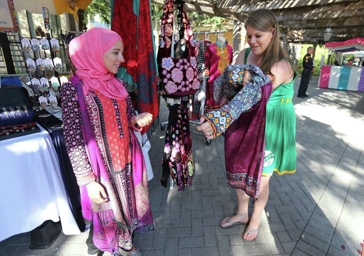 Fuzion Jewelry and Gifts owner Sarah Karbach (left) helps Lynn Denter try on a Kurta Sunday Oct. 4, 2015 during the Muslim Cultural Heritage Society's 6th annual Eid Festival 2015 held at Mayor Maury Maverick Plaza in La Villita.