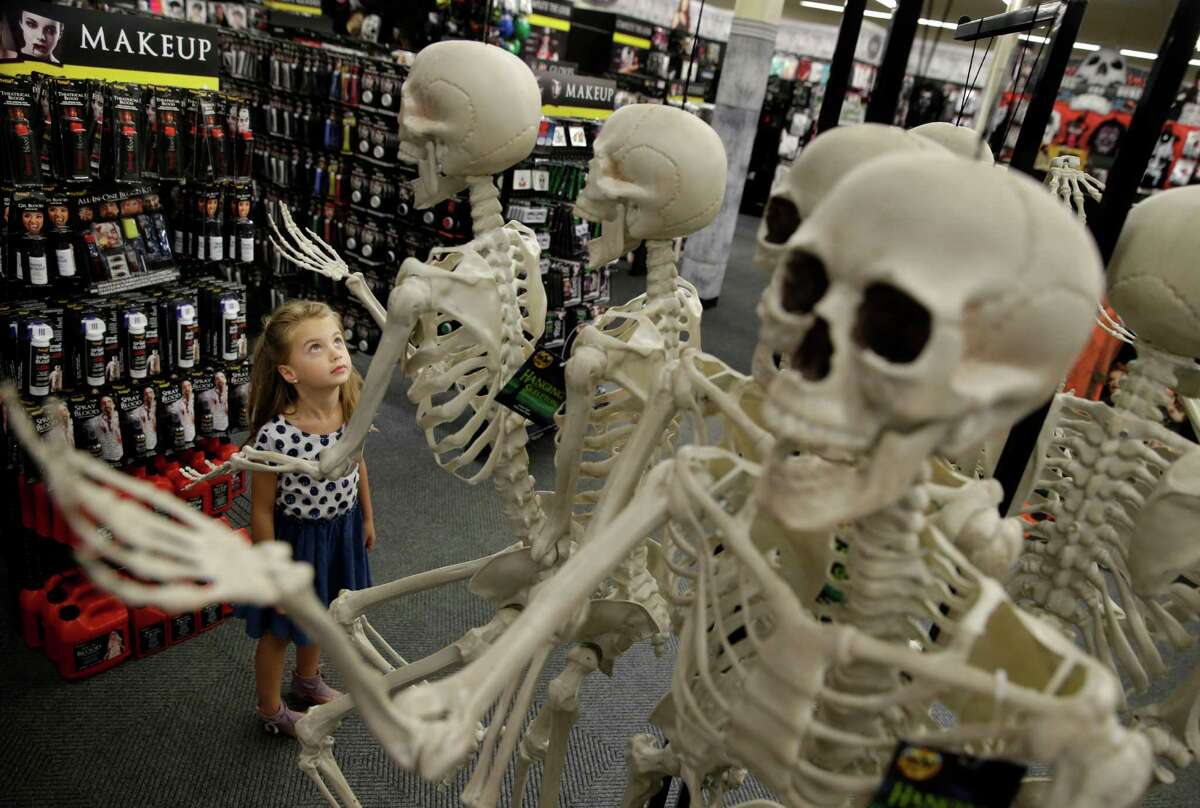 Olivia Vlaicu, 6-year-old of Maywood, N.J., takes an interest in real-looking Halloween skeletons at the Spirit Halloween store in Paramus, N.J. Spirit Halloween, a chain of more than 1,150 pop-up shops across the country, has reincarnated a former Staples store and filled it with 4,000 costumes and accessories with themes ranging from zombies to superheroes and princesses to prison inmates.