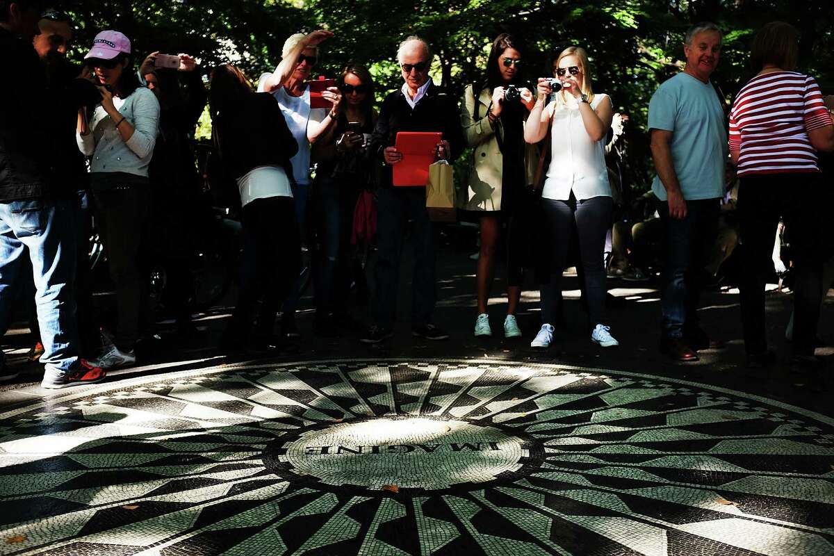 NEW YORK, NY - OCTOBER 06: People stand in Strawberry Fields in Central Park on what would have been John Lennon's 75th birthday on October 6, 2015 in New York City. The area in Central Park is dedicated to the memory of the former Beatle. Lennon lived blocks away at the Dakota residence where he was murdered. (Photo by Spencer Platt/Getty Images) ORG XMIT: 583205341