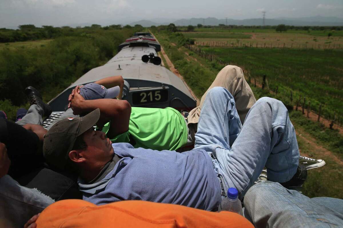 JUCHITLAN, MEXICO - AUGUST 06: Central American immigrants fall asleep on top of a freight train on August 6, 2013 near Juchitlan, Mexico. Thousands of Central American migrants ride the trains, known as 'la bestia', or the beast, during their long and perilous journey north through Mexico to reach the U.S. border. Some of the immigrants are robbed and assaulted by gangs who control the train tops, while others fall asleep and tumble down, losing limbs or perishing under the wheels of the trains. Only a fraction of the immigrants who start the journey in Central America will traverse Mexico completely unscathed - and all this before illegally entering the United States and facing the considerable U.S. border security apparatus designed to track, detain and deport them. (Photo by John Moore/Getty Images)