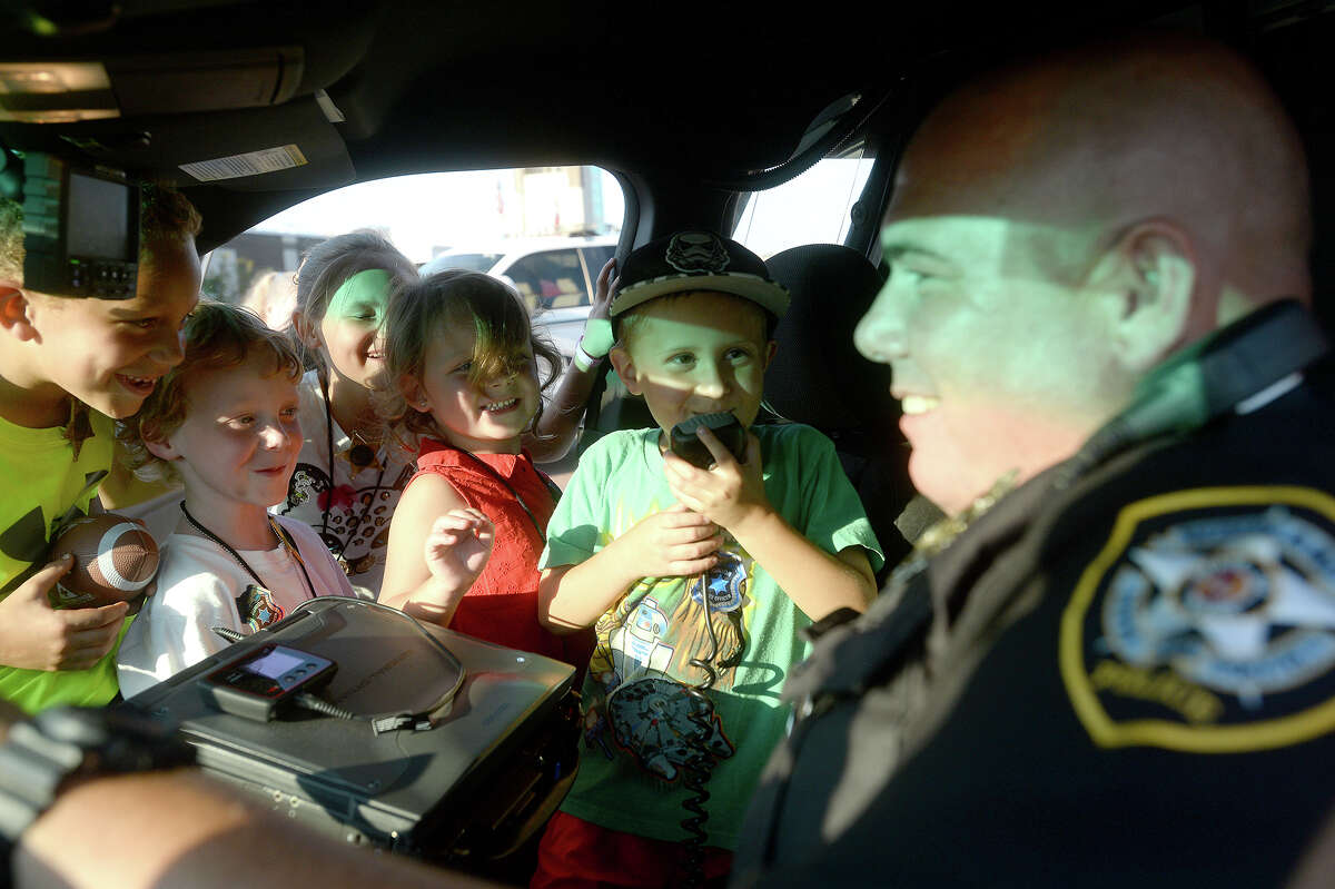 Preston Long, 5, says a hello on the police radio with the assistance of Nederland Police officer Jeremy Reese during the National Night Out event for the community on Boston Avenue in Nederland Tuesday night. A number of family friendly activities were held, as well as displays of police and fire vehicles and safety demonstrations. A similar event was held at the riverfront park in Port Neches, as well as communities across the country. Photo taken Tuesday, October 6, 2015 Photo by Kim Brent