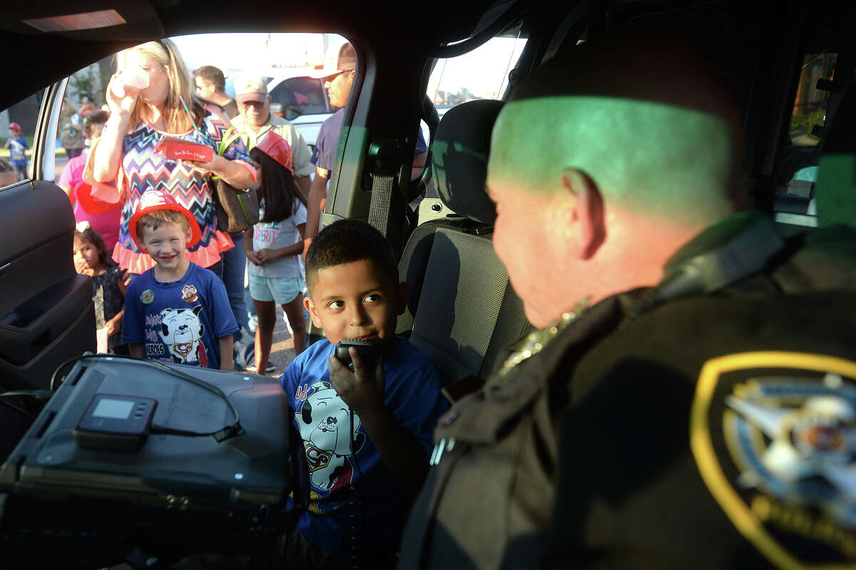Danny Reyes, 5, says a hello on the police radio as he takes a visit of the patrol car used by Nederland officer Jeremy Reese during the National Night Out event for the community on Boston Avenue in Nederland Tuesday night. A number of family friendly activities were held, as well as displays of police and fire vehicles and safety demonstrations. A similar event was held at the riverfront park in Port Neches, as well as communities across the country. Photo taken Tuesday, October 6, 2015 Photo by Kim Brent