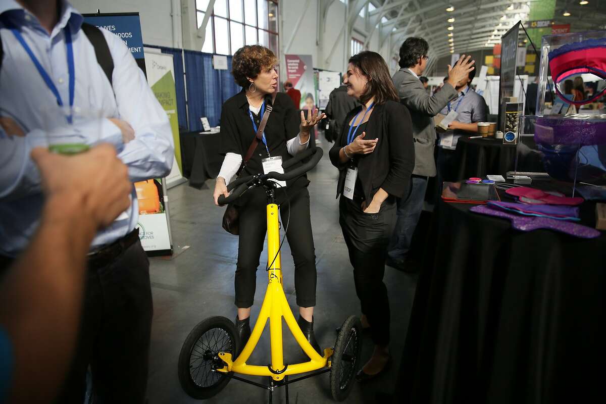 Jennifer North (l to r), Alinker Inventions chief financial officer and Diana Sierra, co-founder BeGirl.org, talk as North rides an Alinker while talking with Sierra at the BeGirl.org booth during Socap2015 at Fort Mason on Wednesday, October 7, 2015 in San Francisco, Calif.