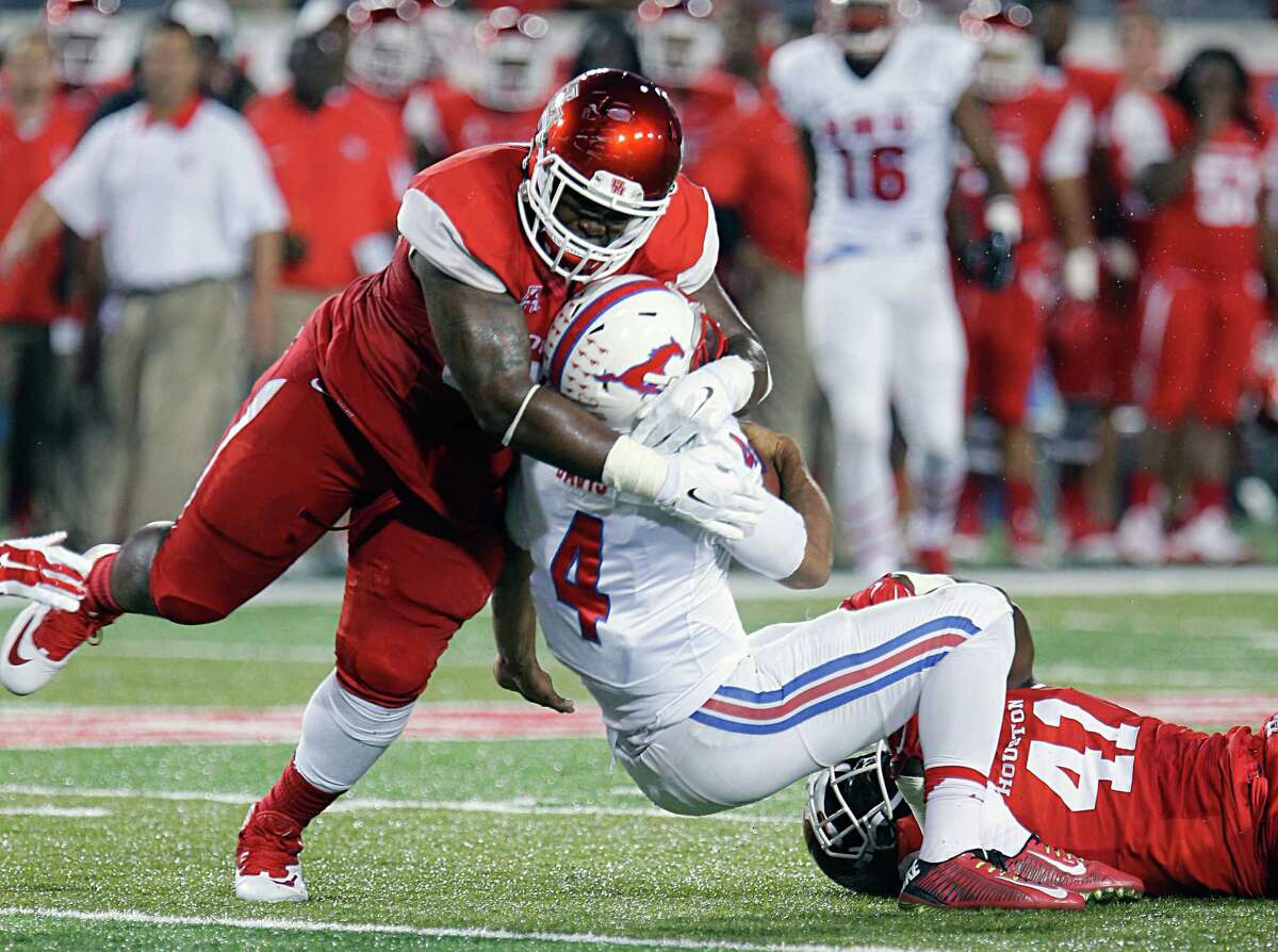 Houston Cougars defensive tackle Tomme Mark left, and Cougars linebacker Steven Taylor right, tackle Southern Methodist Mustangs quarterback Matt Davis center, during the first half of men's college football game action at TDECU Stadium Thursday, Oct. 8, 2015, in Houston.