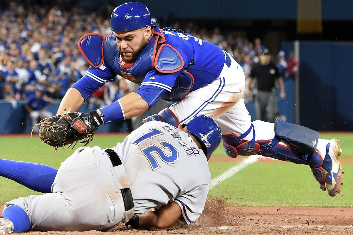Blue Jays catcher Russell Martin, top, fails to tag out the Rangers' Rougned Odor in the 14th inning.﻿
