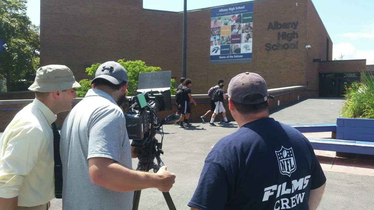 Members of an NFL Films crew shoot scene shots outside of Albany High School in July 2015 for a feature on former Albany High football legend Charlie Leigh. Paul Camarata, the film's producer and a Guilderland native, is at the left. (NFL Films photo)
