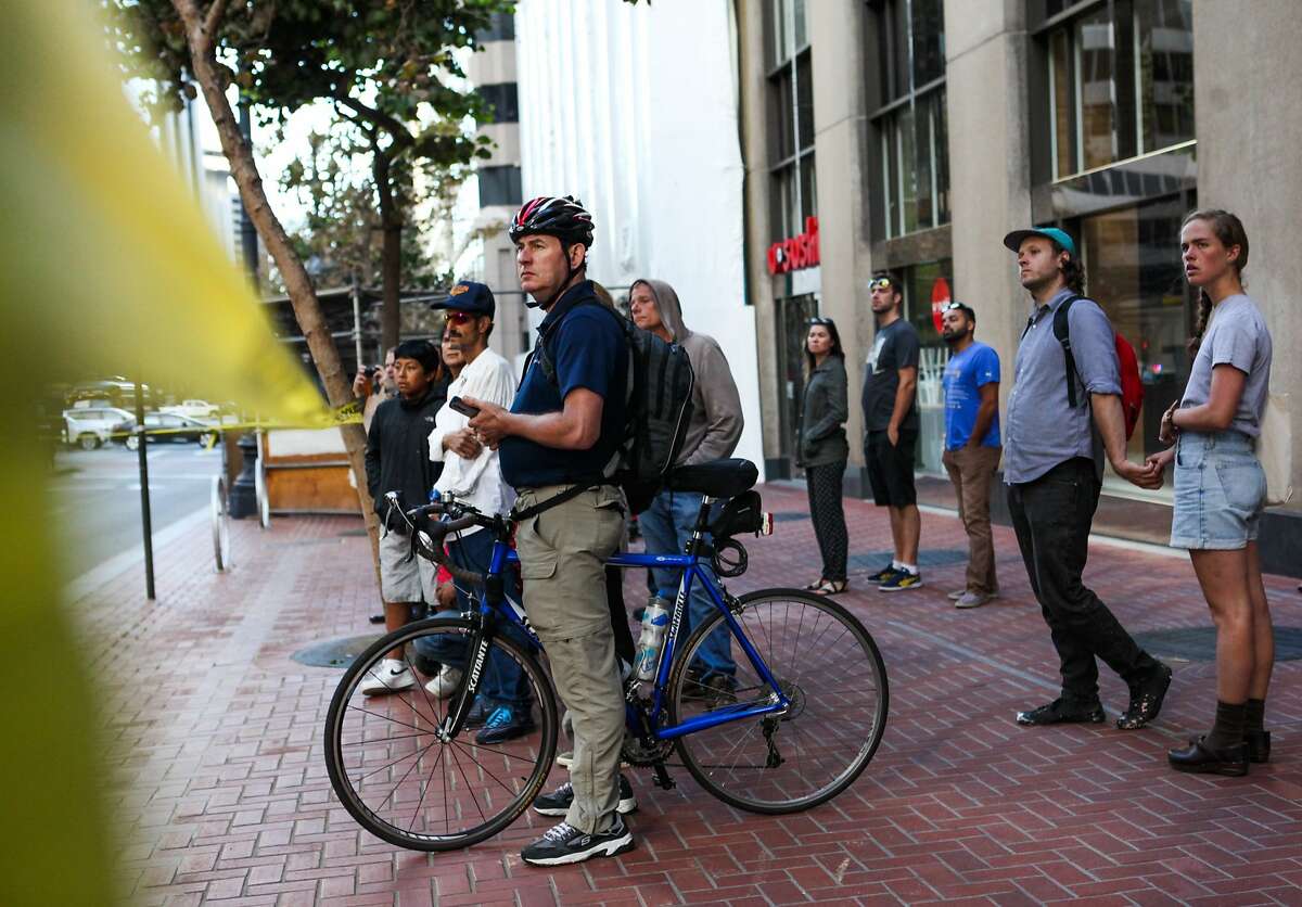 A bicyclist was struck and killed by a Muni bus on Market Street in San Francisco, California on Sunday, October 11, 2015. A crowd watches the scene of the accident.