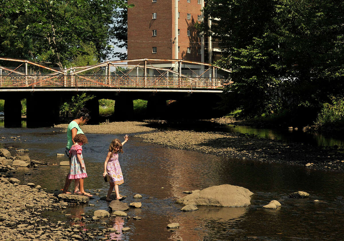 Siobhan Milton,7, right, ventures on her own in front of her sister Anya Milton, 4, and their baby sitter Eileen LaBaire as they explore the banks of the Mianus River in the Mill River Park in Stamford, Conn., on Wednesday, Aug. 28, 2013.