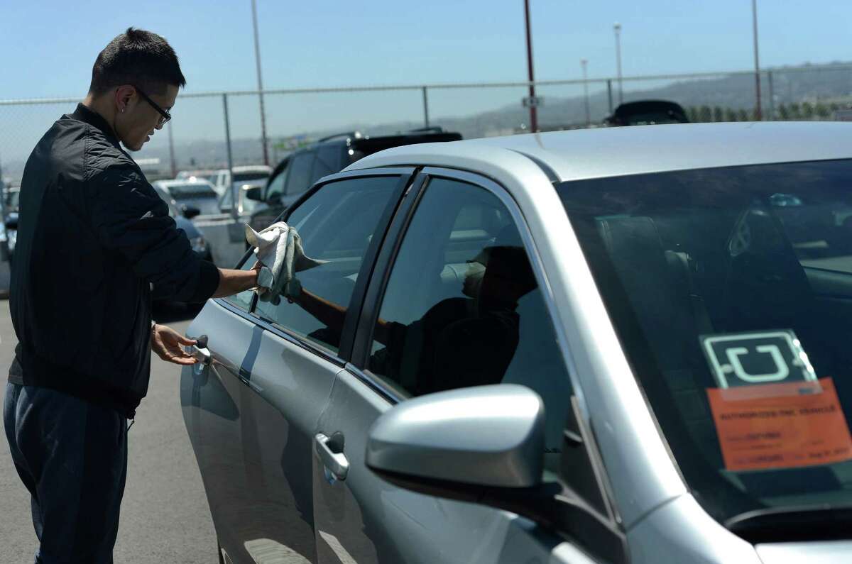 Uber driver Idertsog Darhkan, 23, cleans his car in a parking lot near San Francisco International Airport in June. Some disgruntled UberX drivers and ex-drivers plan to refrain from working this weekend.