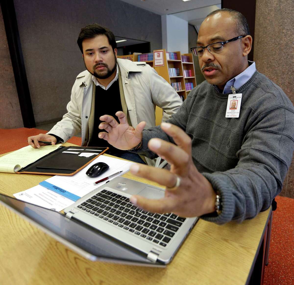 Herb Shook, right, helps David Ortez of Houston get information on the Affordable Care Act last year. ﻿