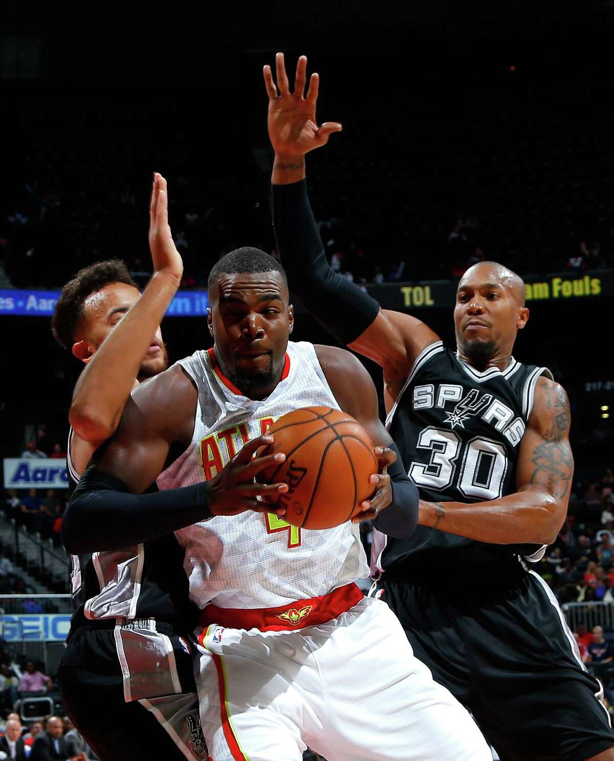 ATLANTA, GA - OCTOBER 14: Paul Millsap #4 of the Atlanta Hawks drives against Kyle Anderson #1 and David West #30 of the San Antonio Spurs at Philips Arena on October 14, 2015 in Atlanta, Georgia. NOTE TO USER User expressly acknowledges and agrees that, by downloading andor using this photograph, user is consenting to the terms and conditions of the Getty Images License Agreement.