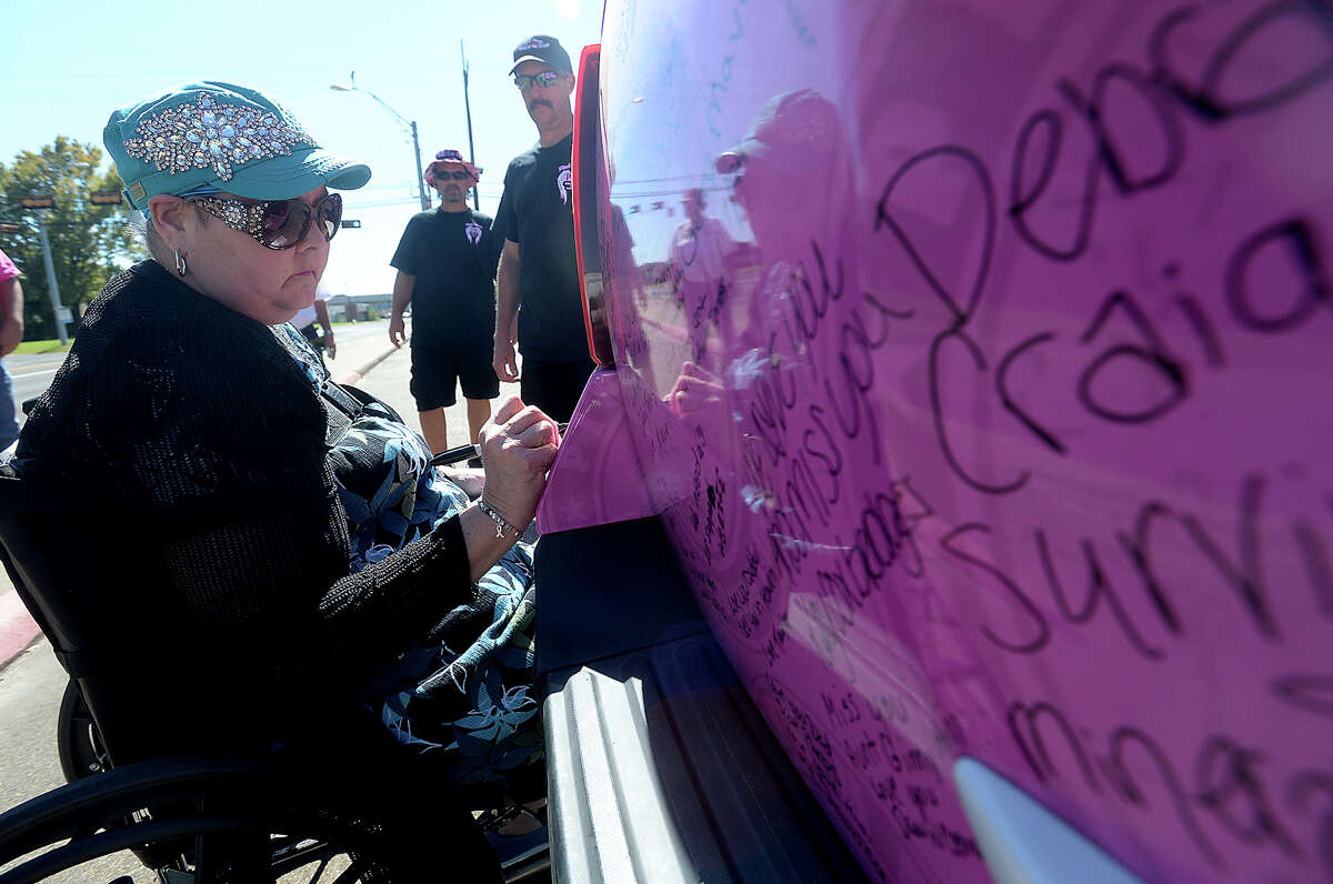 Robbie Reeves signs the survivor's message space on the back of one of the pink painted vehicles in the Pink Heals Tour, which made a stop in Silsbee Wednesday. Reeves is on leave from her job as principal at Kirby Elementary School as she continues to battle uterine cancer, which has spread throughout her body. Tuesday, she had neurosurgery to radiate tumors that were found in her brain, and was glad to be able to come out and add her message of hope to the tour. The national tour helps raise money for cancer research, which is given to each state in which the funds were raised. The non-profit group supports local efforts to battle cancer and assist those struggling with the disease. The caravan of pink fire trucks and other vehicles made a stop at Read Turrentine Elementary before heading to Community Bank, where it would remain open to the public throughout the afternoon. Photo taken Wednesday, October 14, 2015 Kim Brent/The Enterprise