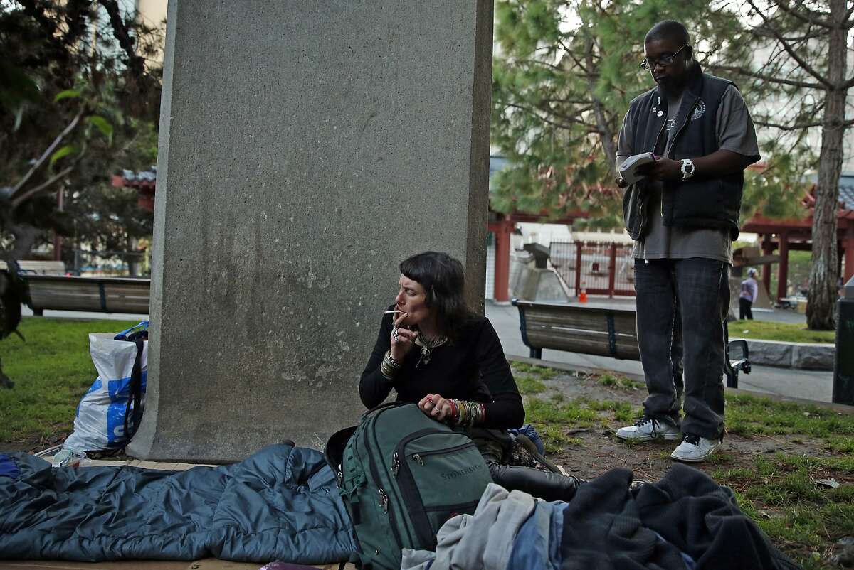 SF Homeless Outreach Team's Hugh Gregory waits for homeless woman Katrina Newsome to finish her cigarette before helping her relocate from Portsmouth Square to the Navigation Center in the Mission District in San Francisco, Calif., on Tuesday, October 13, 2015.