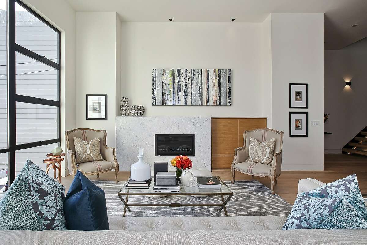 A chic gas fireplace with marble surround serves as a focal point in the living room of the remodeled Noe Valley home.