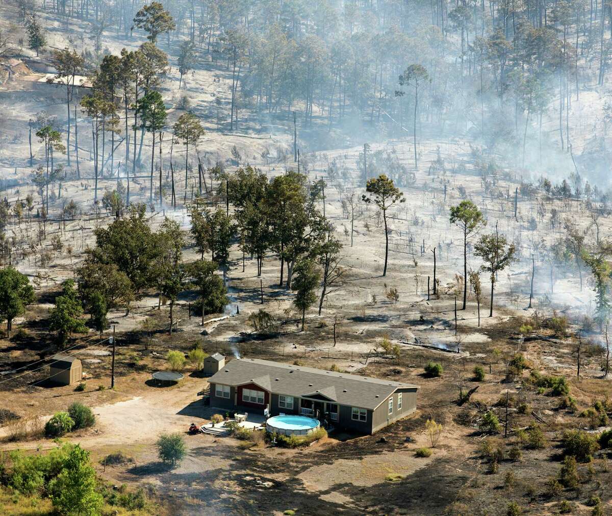 An apparently undamaged home stands in the remains of the Hidden Pines wild lands fire Thursday morning Oct. 15, 2015 in Bastrop County. Officials say it will take several days to gain control of the fire burning just west of Bastrop.
