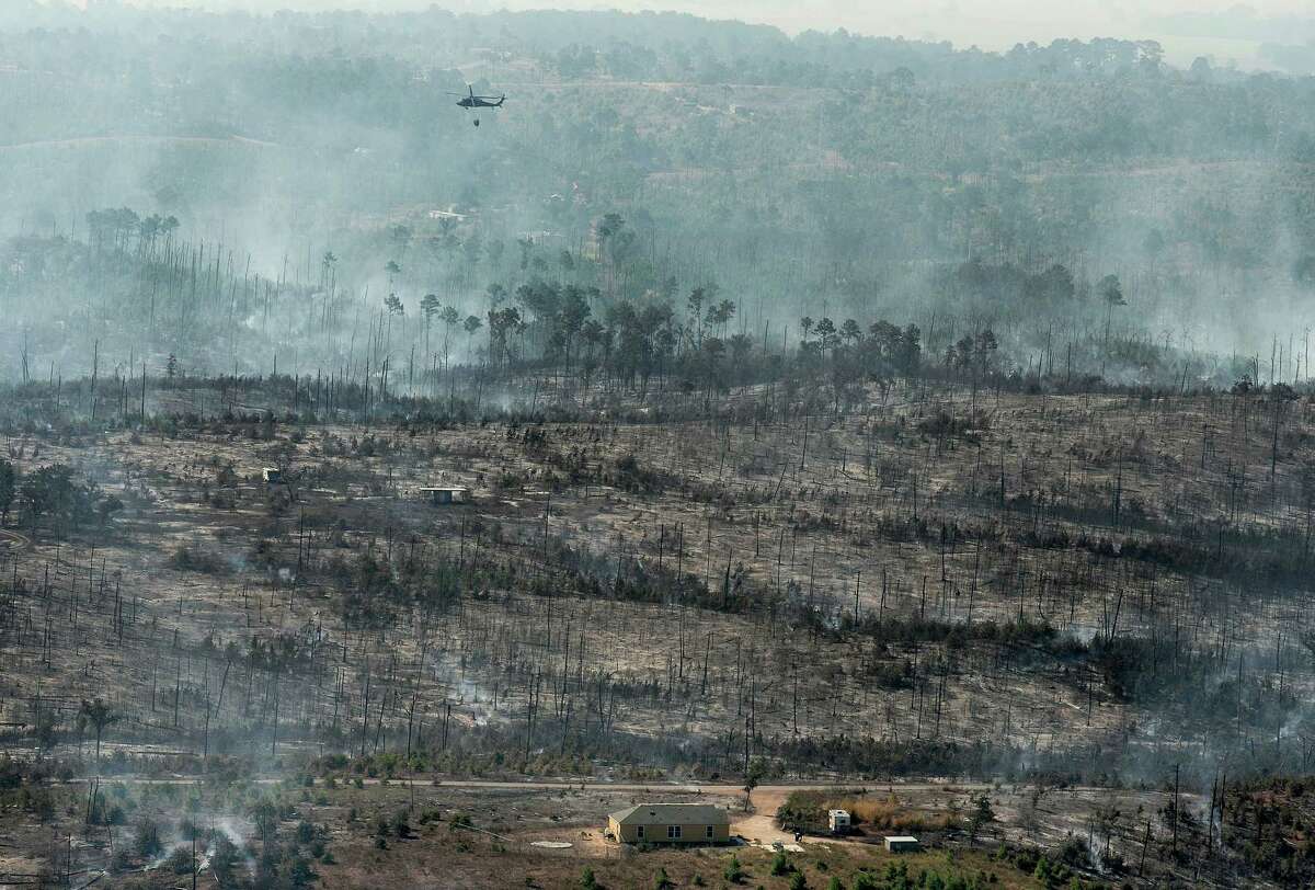 In this aerial photo, a National Guard helicopter uses a bucket to drop water on the Hidden Pines Fire near Smithville, Texas, Friday, Oct. 16, 2015. A preliminary investigation indicates a farming accident sparked the wildfire that's consumed more than 7 square miles and destroyed 40 structures in Central Texas, authorities said Friday. (Rodolfo Gonzalez/Austin American-Statesman via AP) AUSTIN CHRONICLE OUT, COMMUNITY IMPACT OUT, INTERNET AND TV MUST CREDIT PHOTOGRAPHER AND STATESMAN.COM, MAGS OUT; MANDATORY CREDIT