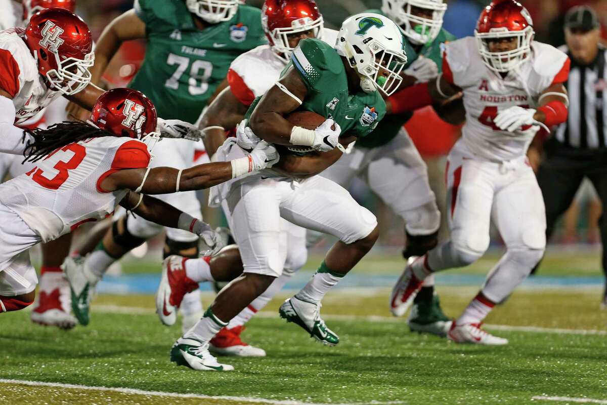 UH safety Trevon Stewart (23) attempts to tackle Tulane running back Dontrell Hilliard, center, in the first quarter Friday night at Yulman Stadium in New Orleans. The stingy Cougars defense allowed the Green Wave offense only 262 yards total.