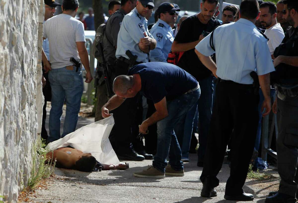 Israeli police stand around the body of a Palestinian in Jerusalem Saturday, Oct. 17, 2015. Police spokeswoman Luba Samri said a 16-year-old Palestinian drew a knife on officers when they approached him in Jerusalem and asked for identification Saturday. She said the officers opened fire and killed him. (AP Photo/Mahmoud Illean)
