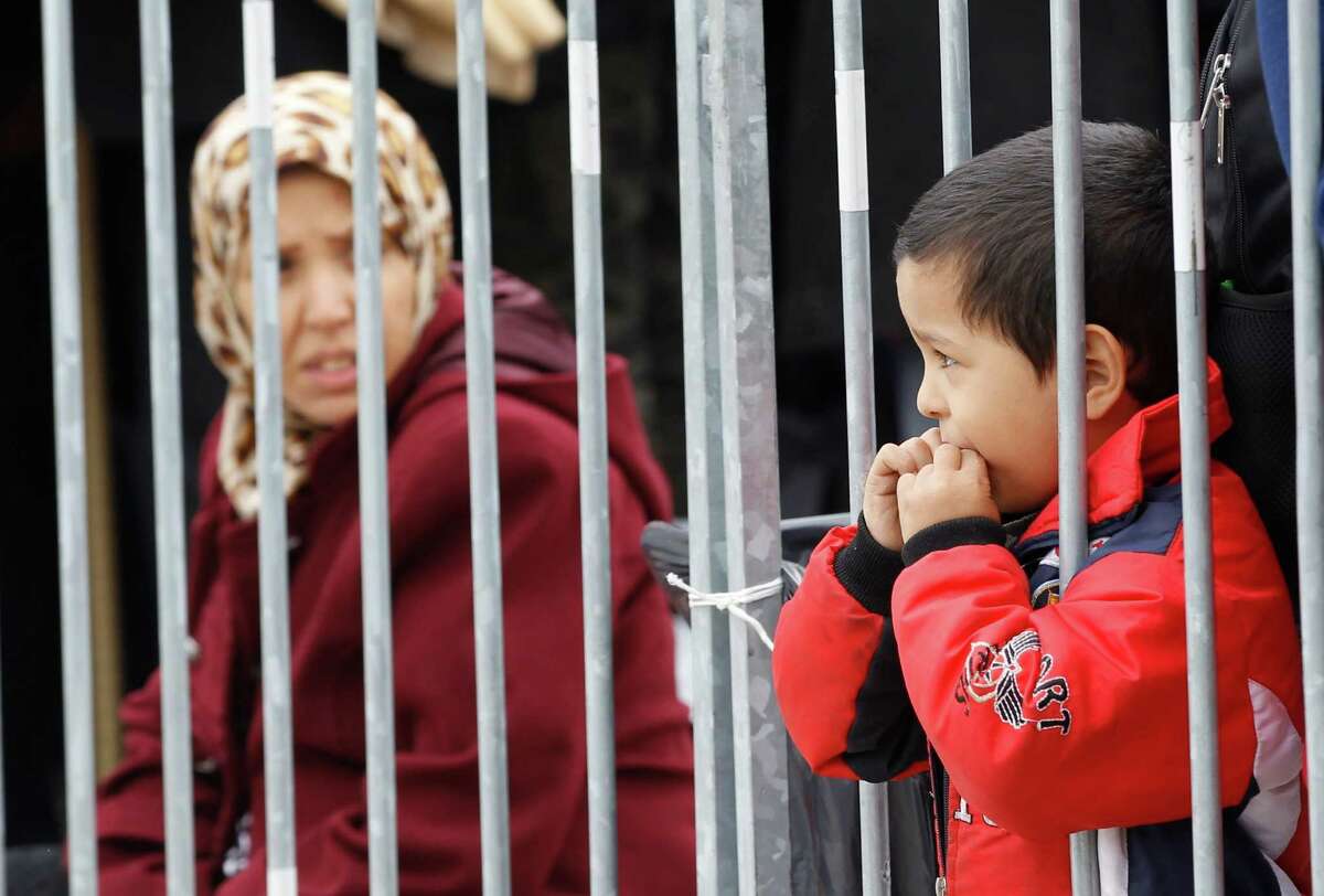 Young boy looks through bars as group of migrants waits to be registered after they arrive from Croatia in Sredisce ob Dravi, Slovenia, Sunday, Oct. 18, 2015. Hungary shut down its border with Croatia to the free flow of migrants, prompting Croatia to redirect thousands of people toward its border with Slovenia. (AP Photo/Petr David Josek)