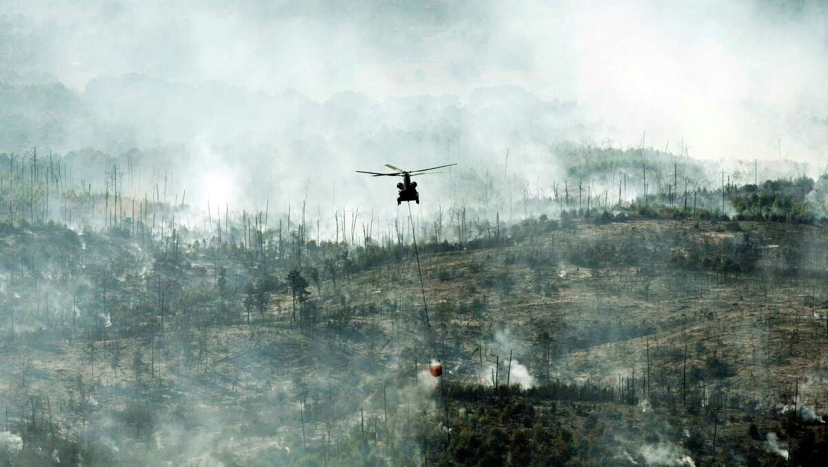 A helicopter on Friday drops water on the Hidden Pines fire in Smithville. A preliminary investigation indicates a farming accident sparked the wildfire. ﻿
