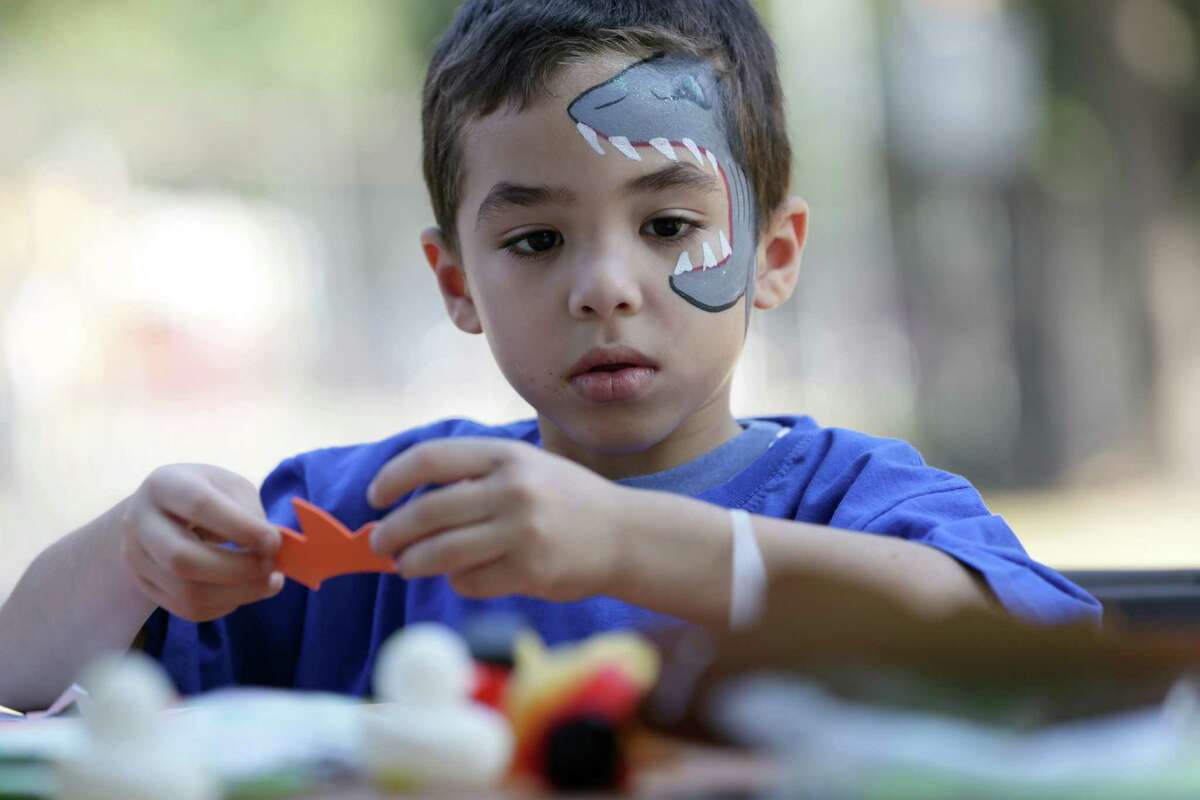 Dominic Chavez, 6, works on a Halloween mask as he and others took advantage of the pleasant weather Sunday to attend the Volunteer Houston 2015 Volunteer Fair at Sam Houston Park.