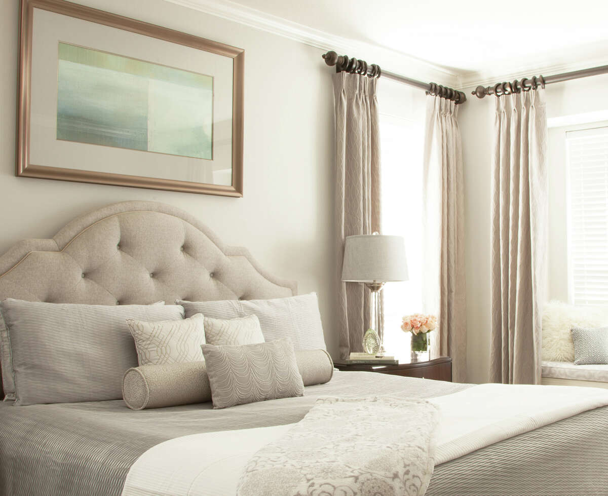 This master bedroom has a tufted fabric headboard, but that feminine detail is balanced out with a neutral color palette and clean-lined furniture.